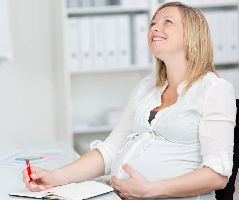 Schwangere Mitarbeiterin hält sich die Hand an den Bauch